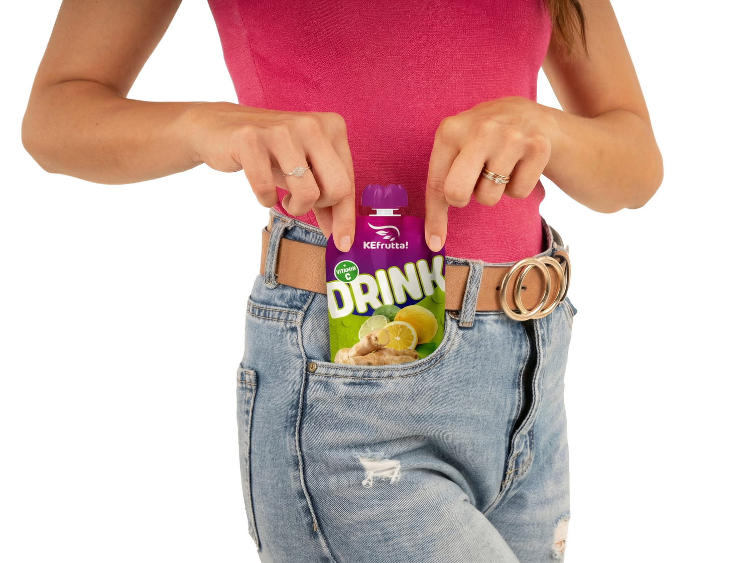 Eine Frau in einem pinken Oberteil und einer hellblauen Jeans steckt eine lilafarbene Trinkpackung der Marke KEfrutta mit Zitrone und Ingwer in ihre Hosentasche.